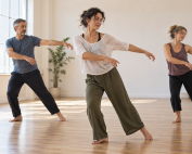Tre adulti durante una lezione di danza in una sala luminosa